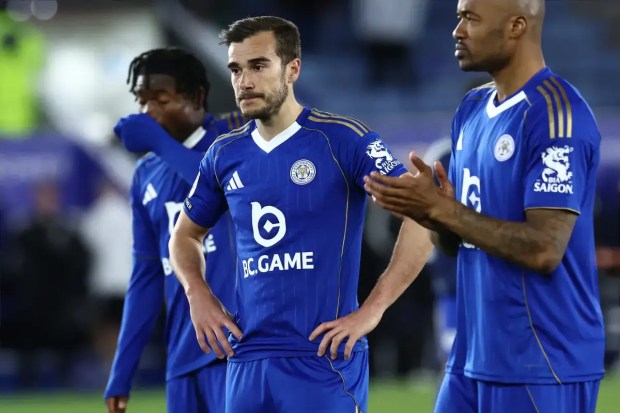 Leicester City players stand with disappointed looks on their faces.
